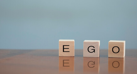 wooden alphabet blocks reading - Ego - balanced in the palm of his hand in a conceptual image.