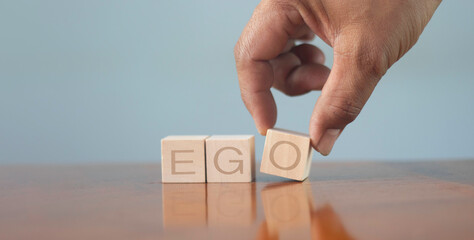 wooden alphabet blocks reading - Ego - balanced in the palm of his hand in a conceptual image.