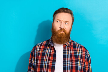 Photo of funky doubtful guy wear checkered shirt looking empty space isolated blue color background