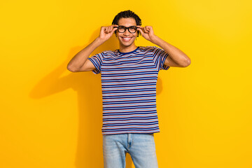 Portrait of positive smart person toothy smile arms touch glasses isolated on vibrant yellow color background