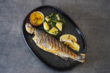 Closeup of a plate of freshly grilled fish and herbs and lemon © Omar Tursić/Wirestock Creators