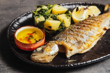 Closeup of a plate of freshly grilled fish and herbs and lemon