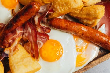 Closeup of a breakfast plate of fried eggs, bacon and sausages