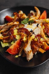 Vertical closeup of a bowl of salad with chicken slices, tomatoes and lettuce