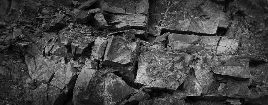 Black white dark gray stone rock texture background for design. Grunge. Cracked crumbled weathered rough mountain surface. 3d shape. Close-up. Rocky, basalt, granite. Nature.