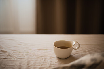 Cup of the morning coffee on the bedsheet
