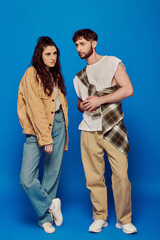 fashionable couple, casual wear, posing on blue backdrop, bearded man, brunette woman, bold makeup