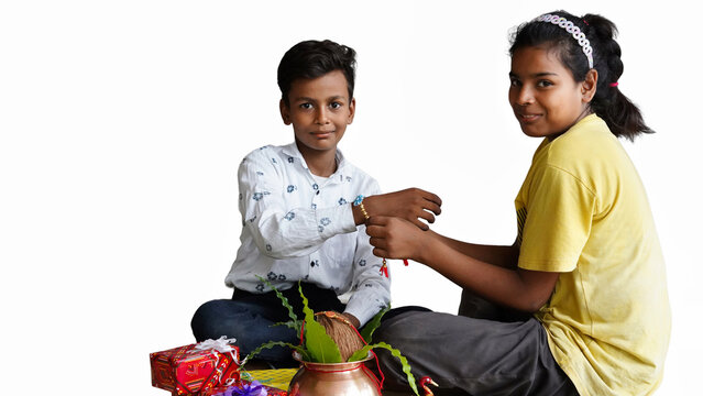 Image of Indian, Hindu girl tying a rakhi around the wrist of her brother.