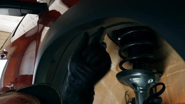 Man at a service station unscrews bolts and clips that fix wheel arch extender