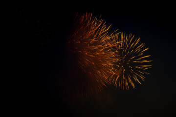 Beautiful gold colored fireworks explodes in night city sky above and though smoke cloud isolated on black. Pyrotechnic display. Copy space for your text or decoration. Holiday celebration theme.