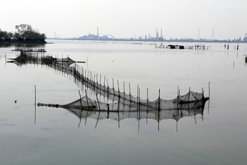 View of shellfish tables and fishing baskets in the Venice bay from the Ponte della liberta - Industrial estate in the horizon - Venice - Italy