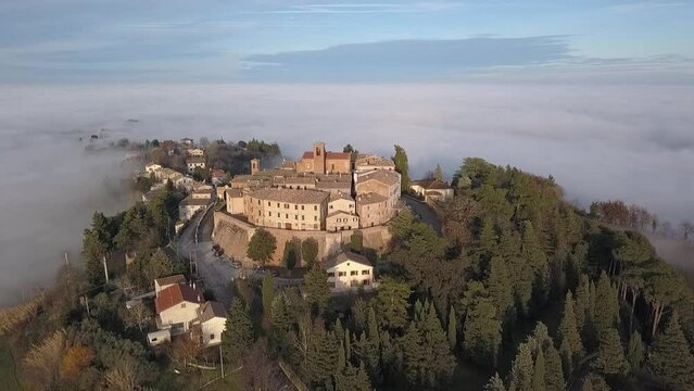 Aerial view of medieval village of Piticchio with old buildings and trees covered by clouds