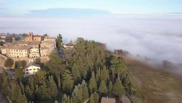 Aerial view of medieval village of Piticchio with old buildings and trees covered by clouds