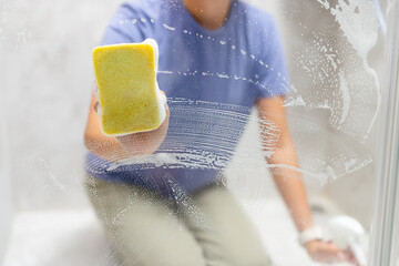 Woman remove hard water stains and deposits in bathroom