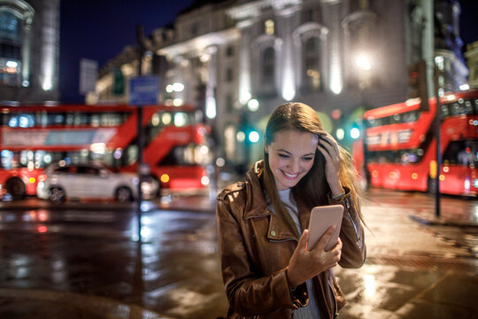 Young caucasian woman using a smart phone at the Piccadilly Circus in London UK at night