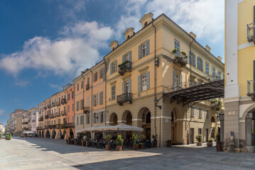 Fototapeta na wymiar Cuneo, Piedmont, Italy - August 16, 2023: Cityscape on Roma Street main pedestrian cobblestone street with Ancient buildings decorated and with arcade in historic center