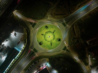 Aerial view of a road busy with cars regulated by a roundabout at night