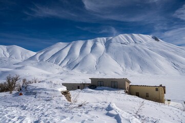 Landscape of sow covered white peaks of majestic mountains in Castelluccio di Norcia in wintertime