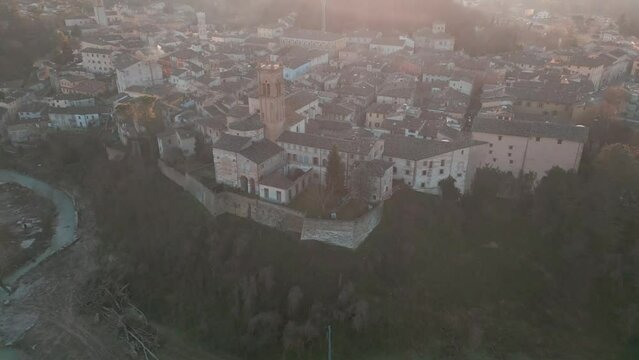 Drone footage flyover the medieval Comune of Mondaino, Rimini province, Marche, Italy at sunset