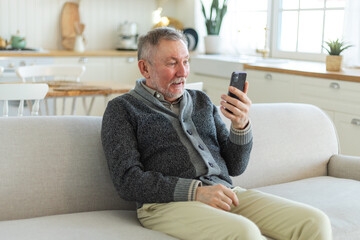 Obraz premium Happy middle aged senior man talk on video call with friends family. Laughing mature old senior grandfather having fun speaking with grown up children online. Older generation modern tech usage