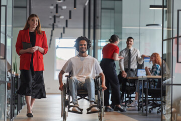 A group of young business people in a modern glass-walled office captures the essence of diversity and collaboration, while two colleagues, including an African American businessman in a wheelchair