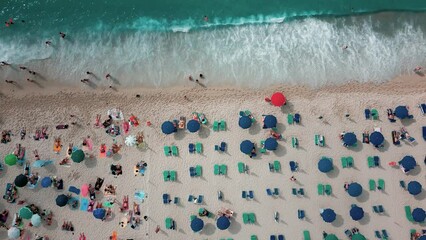 Aerial top view video of sun loungers, beach umbrellas and people on the sea shore