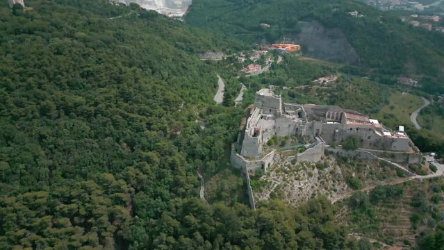 Drone shot over Arechi Castle on a green forested hill