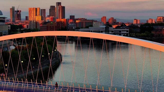 Golden sunset over a Salford Quays foot bridge, people passing by over the bridge. 