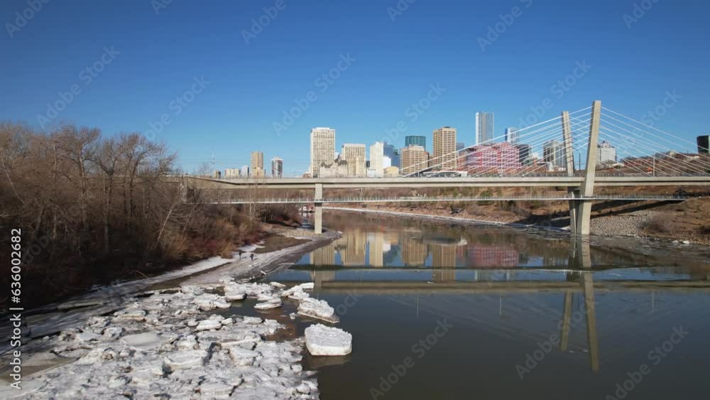 Wall mural Aerial of a calm river under the bridge with buildings against the blue sky in the background