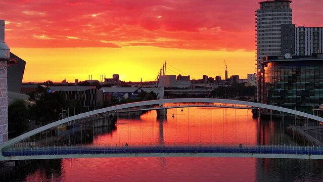 Golden sunset over a Salford Quays foot bridge, people passing by over the bridge. 
