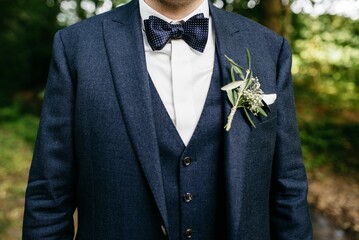 Confident-looking young man in a sharp blue suit and bow tie stands with his hands in his pockets