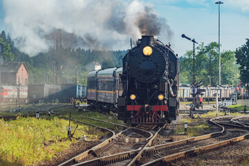 Retro steam train departs from the platform.