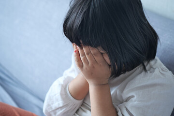 a upset child girl cover her face with hand 