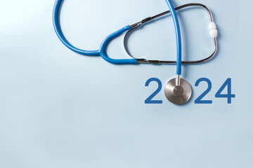 Blue stethoscope and numbers 2024 on pastel background. The concept of health care in the New Year. Selective focus, copy space