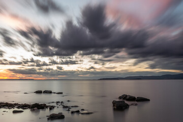 Long exposure view of rocks in Trasimeno lake Umbria, with moving clouds at dusk - 636012699