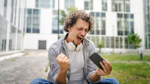 man use mobile smart phone play video games sit outdoor