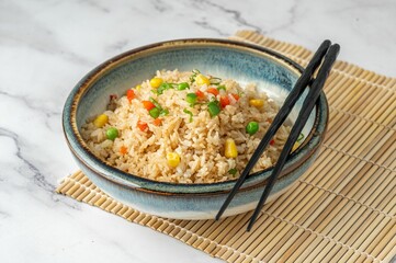 Overhead view of a bowl of rice and vegetables with chopsticks on it