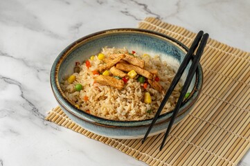 Overhead view of a bowl of chicken and rice with chopsticks on it