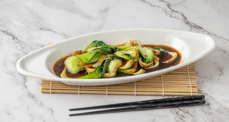 White, oval-shaped bowl filled with fresh bok choy