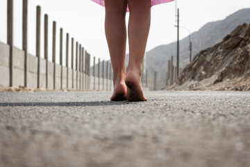 Pies descalzos de una niña en la carretera en un día soleado de verano.