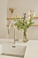 some flowers in a vase on the kitchen sink with wooden shelves and shelvings behind it to be used for storage