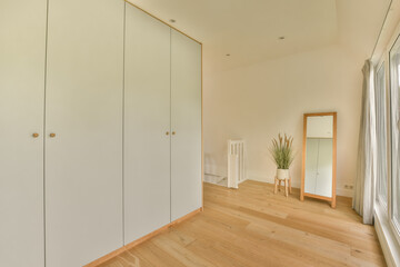 Obraz premium an empty room with white cupboards and a plant in the corner on the right hand side of the room