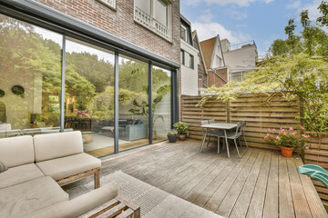 a patio with wooden decking and glass doors leading to an outdoor living area that looks out onto...