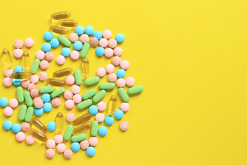 Vitamins of different colors on a yellow background. Top view of a bunch of bright pills. Pharmaceutical industry. Health care and medicine. Pharmacy product. Banner, copy space