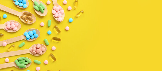 Vitamins of different colors in wooden spoons on a yellow background. Top view of scattered bright pills. Pharmaceutical industry. Health care and medicine. Pharmacy product. Copy space