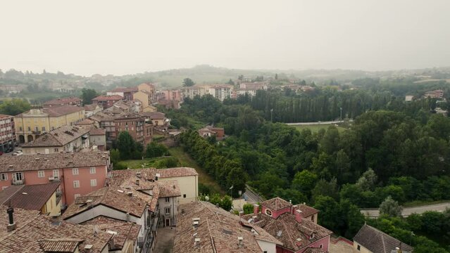 Drone footage over traditional old Costigliole d'Asti houses with trees and misty sky