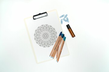 there is some colored pencils on the clipboard with an image