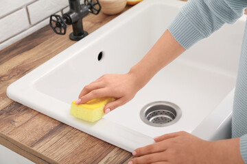 Woman cleaning white sink with sponge and baking soda, closeup