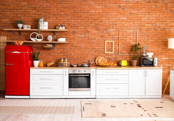 Interior of stylish kitchen with red fridge, counters and shelves