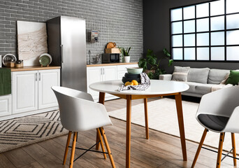 Interior of kitchen with stylish fridge, counters, sofa and table